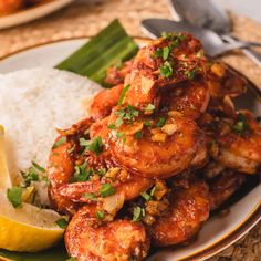 a plate topped with shrimp and rice next to lemon wedges