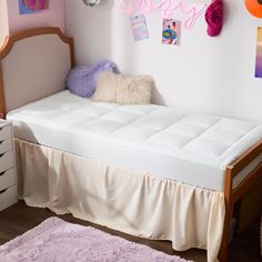 there is a bed with a white mattress on top of it and pink rugs in the corner