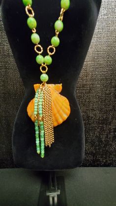 Orange Seashell, Green Beaded, Dangle Drop Chained Necklace Length: 32 inches long Weighs: 2.2 lbs. Pendants size: 55 by 54 mm Beaded Long Necklace For Beach, Summer Beaded Dangle Necklaces, Bohemian Chain Necklaces For Beach, Beach Beaded Dangle Necklaces, Beaded Dangle Necklaces For The Beach, Beaded Chain Dangle Necklaces For The Beach, Elegant Green Necklace For Beach, Beach Necklaces With Round Beads Chain, Colorful Beaded Dangle Necklaces For Beach