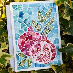 a card that has been made with stained glass and is sitting on some green leaves