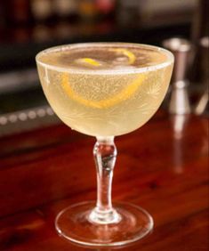 a close up of a wine glass on a table with a drink in the background