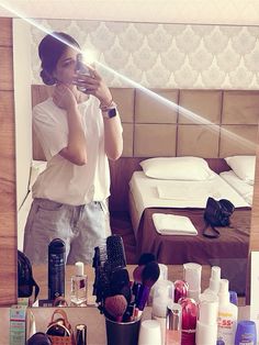 a woman taking a selfie in front of a mirror with cosmetics on the counter