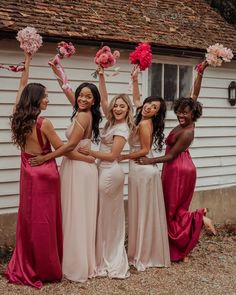 a group of women standing next to each other in front of a house holding flowers