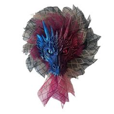 a blue and red dragon head on top of a pink ribbon with leaves around it