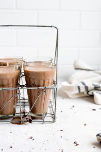 three glasses filled with chocolate milkshakes sitting on top of a white countertop