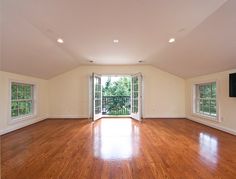 an empty living room with hard wood flooring and large sliding glass doors leading to a balcony