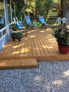 a wooden deck with chairs and plants on the ground next to an outside patio area