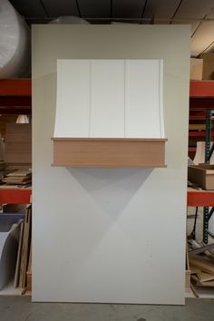 a white wall with some wood on it in a room filled with shelves and other items