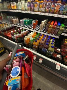 a person pushing a shopping cart in front of a grocery store filled with drinks and condiments