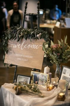 a sign that is on top of a table with flowers and pictures around it in front of people