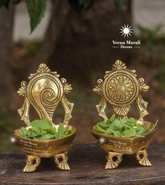 two golden metal bowls with green leaves in them