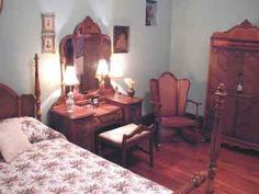 a bed room with a neatly made bed and wooden furniture