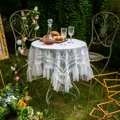 a table that has some food on it in the grass next to chairs and flowers