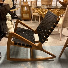 a wooden rocking chair sitting on top of a metal floor next to a glass table