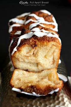 cinnamon roll with white icing on top sitting on a metal tray next to an apple