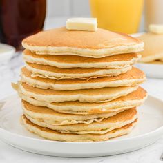 a stack of pancakes on a plate with butter and syrup in the backgroud