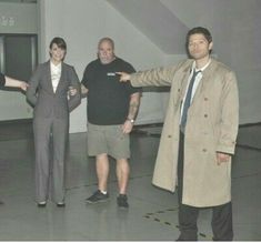 three men in suits and ties are posing for a photo with one man pointing at the camera