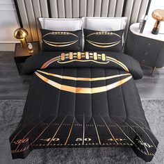 a bed with black and gold comforters on top of it in front of a night stand