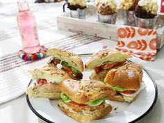 a white plate topped with sandwiches on top of a table next to cupcakes