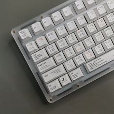 a computer keyboard sitting on top of a gray table next to a black and white mouse