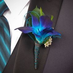 a boutonniere with blue flowers and green leaves on the lapel cover