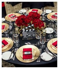 a black table topped with red roses and place settings