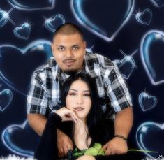 a man and woman posing for a photo with hearts in the background