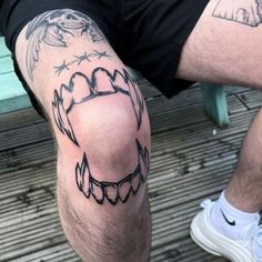 a man is sitting on a bench with his legs crossed and tattoos on the leg