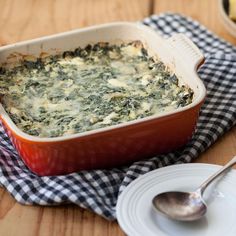 a casserole dish with spinach and cheese in it on a wooden table