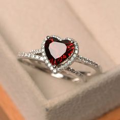 a red heart shaped ring sitting on top of a box