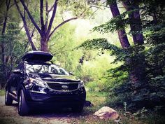 a car parked on the side of a dirt road with its hood up in the woods