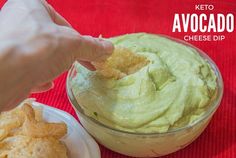 a person dipping guacamole into a bowl