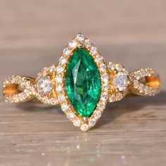 The 81st Avenue: Marquise Emerald And Natural Diamond Ring In Yellow Gold. This Ring Highlights A Central 0.75-Carat Marquise Brilliant-Cut Natural Emerald With A Vivid, Very Slightly Bluish-Green Saturation. Encircling The Emerald Is A Halo Of Round Brilliant-Cut Natural Diamonds, Accentuated By Larger Round Brilliant-Cut Diamonds On Each Side. The Design Is Elegantly Completed With A Twisted Shank Set With Round Brilliant-Cut Natural Diamonds. A Total Of 0.50 Carats Of Diamonds Completes The Ring. Crafted In 14-Karat Yellow Gold, The Ring Is Currently A Finger Size 6.5, With The Option To Be Adjusted To Any Finger Size For An Additional Charge Upon Request. Natural Diamond Ring, Bluish Green, Natural Emerald, Round Brilliant Cut Diamond, Womens Jewelry Rings, Round Brilliant, Natural Diamonds, Gold Color, Diamond Ring