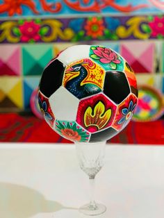 a colorful soccer ball sitting on top of a wine glass