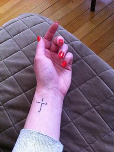 a woman's wrist with a cross tattoo on it