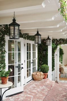 the front porch is decorated with potted plants and hanging lantern lights on either side