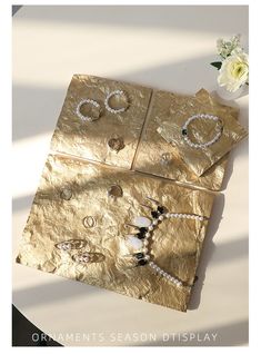 three pieces of jewelry sitting on top of a table next to a vase with flowers