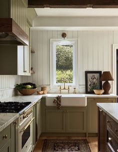 a kitchen with an oven, sink and window in the center is decorated in green