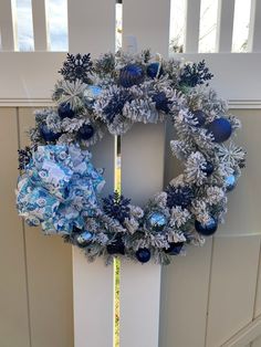 a blue and white christmas wreath hanging on the side of a door