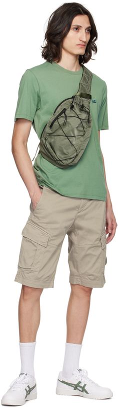 Water-resistant garment-dyed nylon sateen messenger bag in green. · Webbing carry handle · Zip pocket at press-release crossbody strap · Logo-printed acetate lens · Zip pocket at face · Criss-crossing bungee-style drawstring · Padded mesh back face · Zip closure · Patch pockets and lanyard clasp at interior · Canvas lining · H13.5 x W10 x D3.5 Supplier color: Agave green Green Utility Bags With Functional Pockets, Green Utility Bag With Functional Pockets, Green Nylon Shoulder Bag With Functional Pockets, Streetwear Nylon Bag With Side Pockets, Green Utility Shoulder Bag For Outdoor, Nylon Bags For Streetwear, Green Nylon Bag With Multiple Pockets, Casual Green Shoulder Bag With Functional Pockets, White Patches