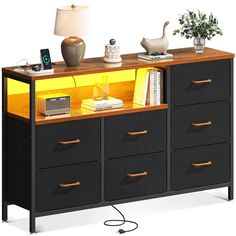 a black and yellow dresser with some books on it's top shelf next to a lamp