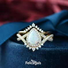 an opal and diamond ring sits on top of a blue cloth