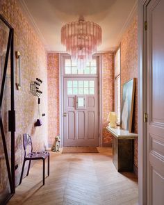 the hallway is decorated with pink wallpaper and a chandelier hanging from the ceiling