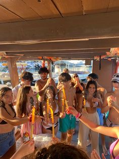 a group of young people standing around each other in front of a boat on the water