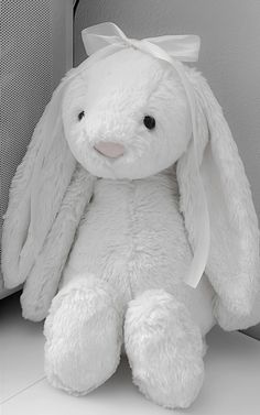 a white stuffed rabbit sitting next to a wall