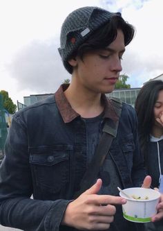 a man holding a bowl of food while standing next to a woman on the street