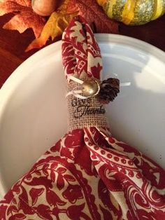 a white plate topped with a red and white napkin next to a pumpkin on top of a wooden table