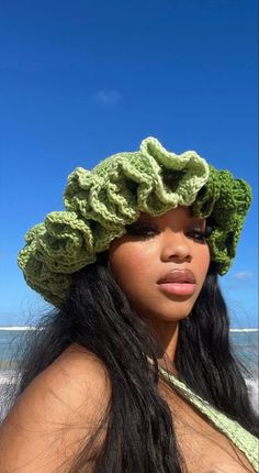 a woman wearing a crocheted hat on top of her head at the beach