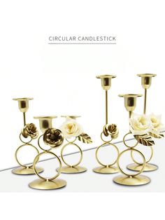 three gold candlesticks with white flowers on them