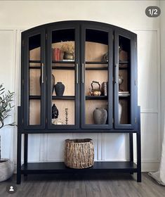 a black china cabinet with glass doors and wicker basket